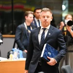 Hungarian official carrying documents at an EU council meeting